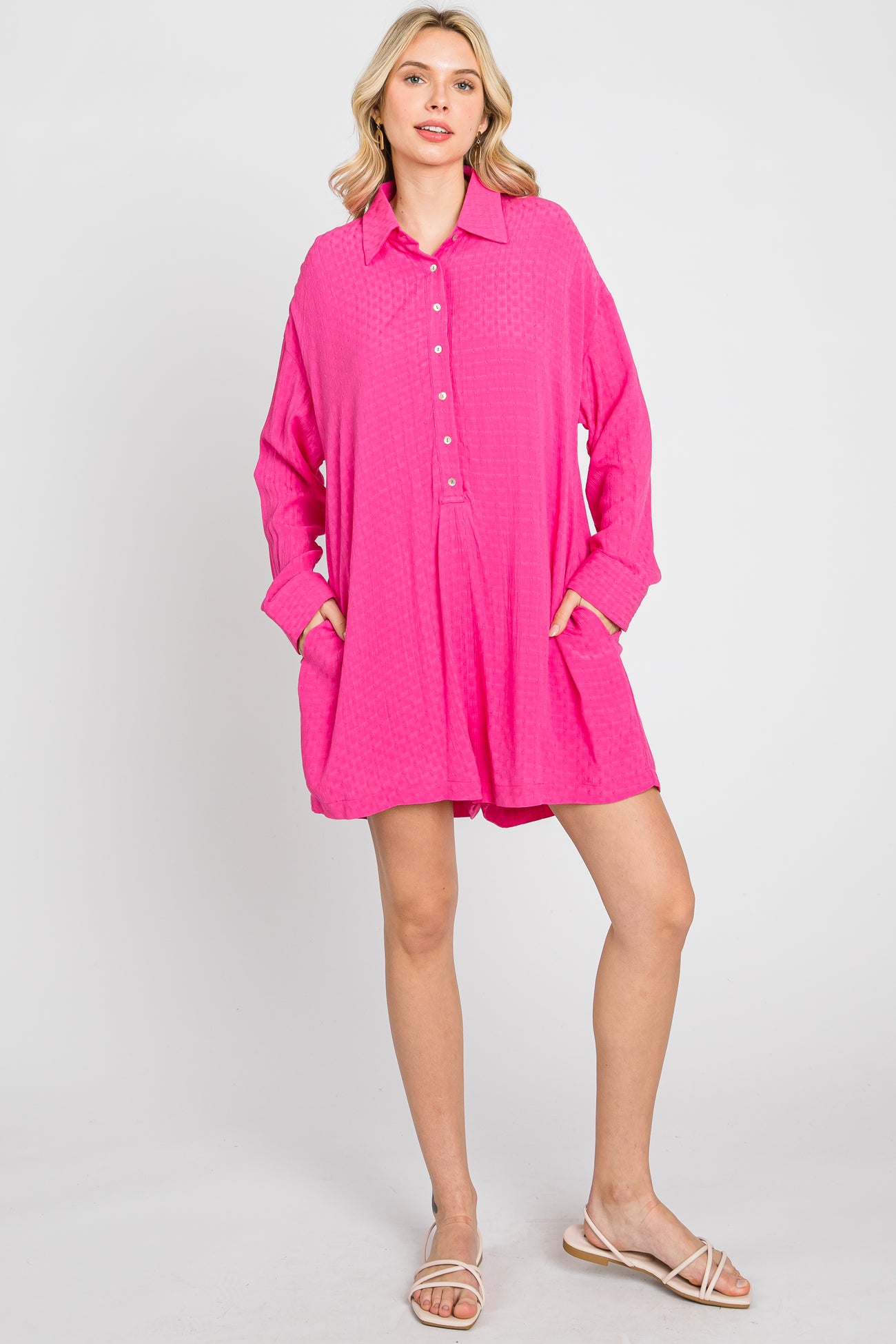 woman wearing a bright pink long sleeve button down shirt dress with pockets and beige sandals