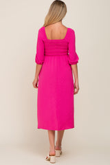 woman wearing a bright pink maternity dress with smocked bodice and three-quarter sleeves, showing her baby bump from the back