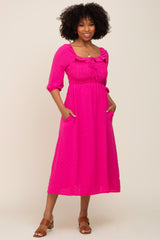 woman wearing a bright pink midi dress with puff sleeves, smocked bodice, and pockets, standing confidently with a smile