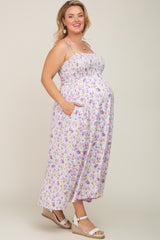pregnant woman wearing a purple floral smocked maternity maxi dress with pockets and white wedge sandals