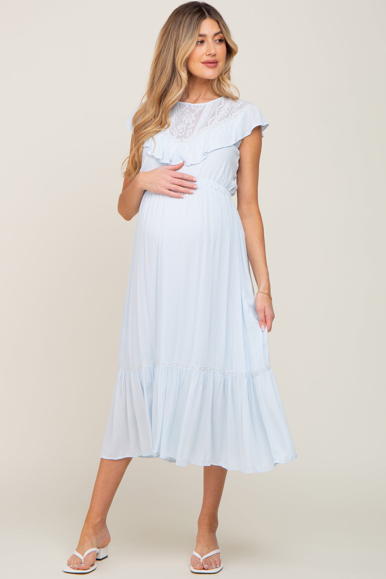 pregnant woman in light blue maternity midi dress with lace detail and ruffled sleeves