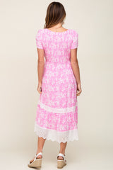 Back view of woman wearing pink floral midi dress with smocked bodice and white eyelet lace trim