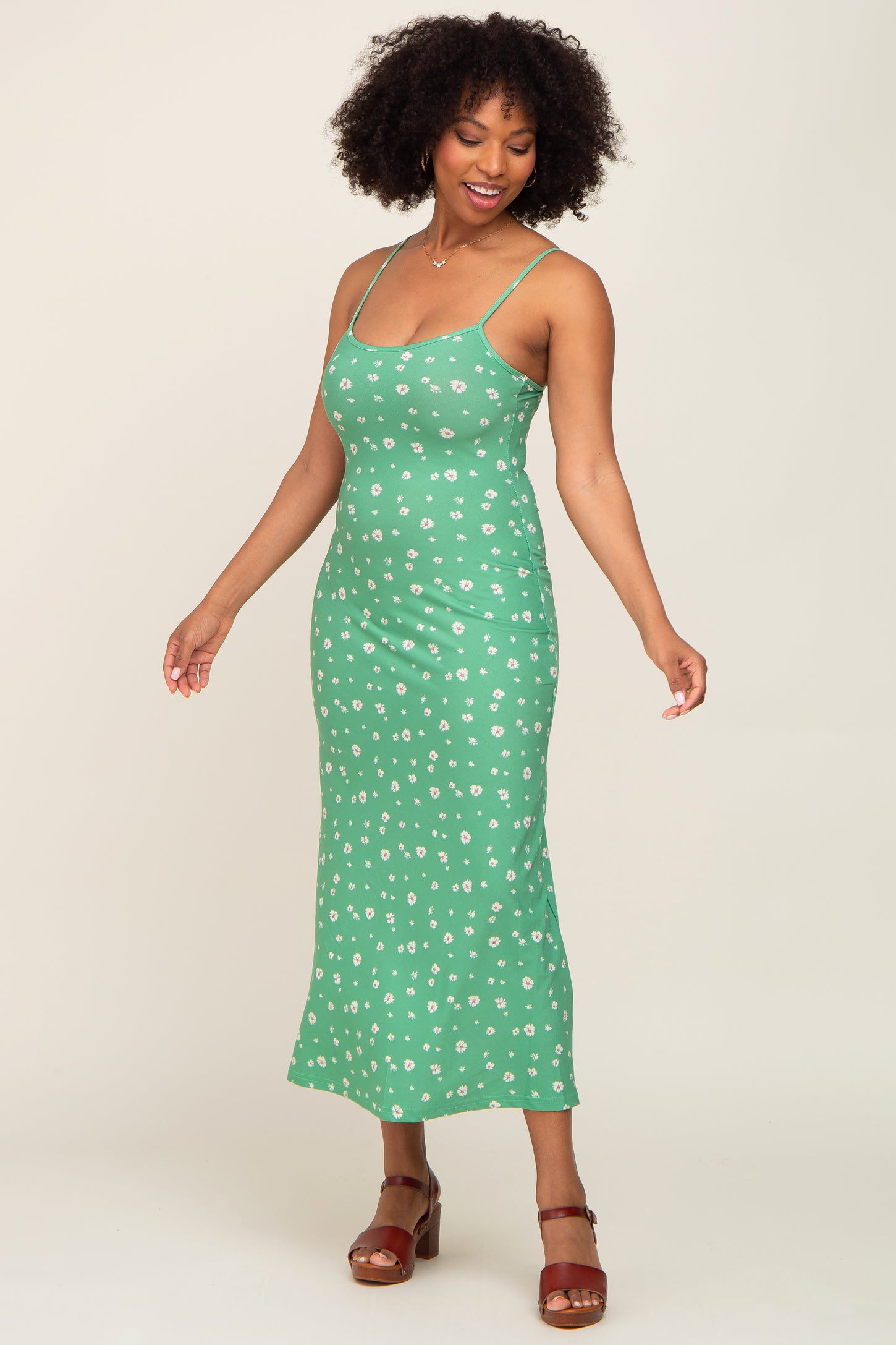 woman wearing a green floral print midi dress with spaghetti straps and brown platform sandals