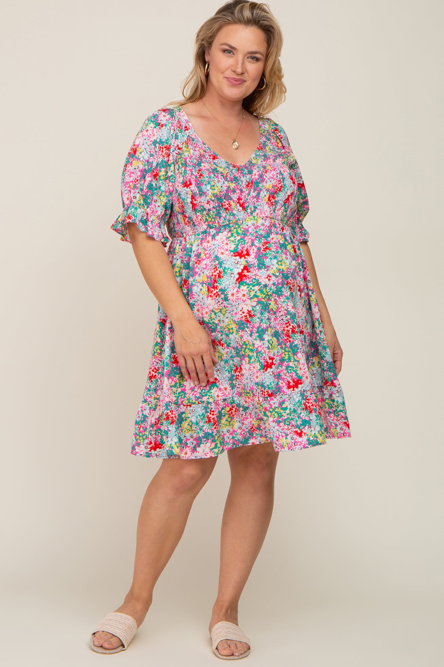 woman wearing a colorful floral print maternity dress with smocked bodice and short puff sleeves