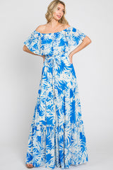 woman wearing a blue and white off-the-shoulder maxi dress with a floral pattern and ruffled sleeves