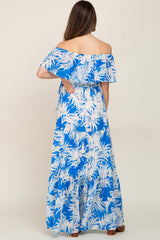 Woman from behind wearing a blue and white tropical palm print off-the-shoulder tiered maxi dress