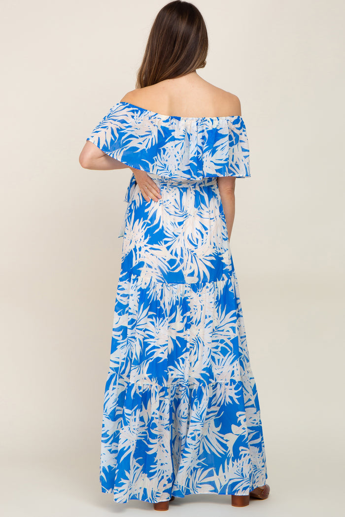 Woman from behind wearing a blue and white tropical palm print off-the-shoulder tiered maxi dress