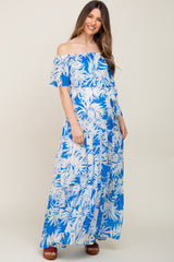woman wearing a blue tropical print off-the-shoulder maternity maxi dress and showing her baby bump