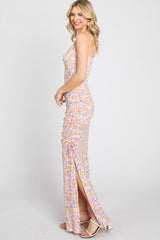woman wearing a floral print sleeveless maxi dress with side slit and ruched detailing