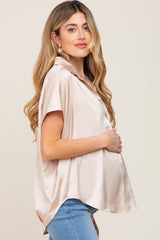 pregnant woman in champagne satin short sleeve maternity top and blue jeans holding her baby bump