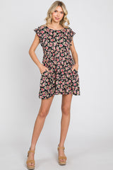 woman wearing a black floral print mini dress with ruffle sleeves and pockets against a white background
