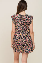 Back view of woman wearing a black floral print mini dress with ruffle sleeves and a tie neck detail