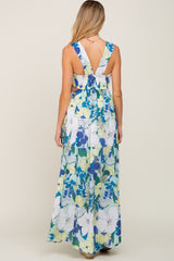 Back view of a woman wearing a blue and yellow floral print maxi dress with a smocked back and v-neck straps