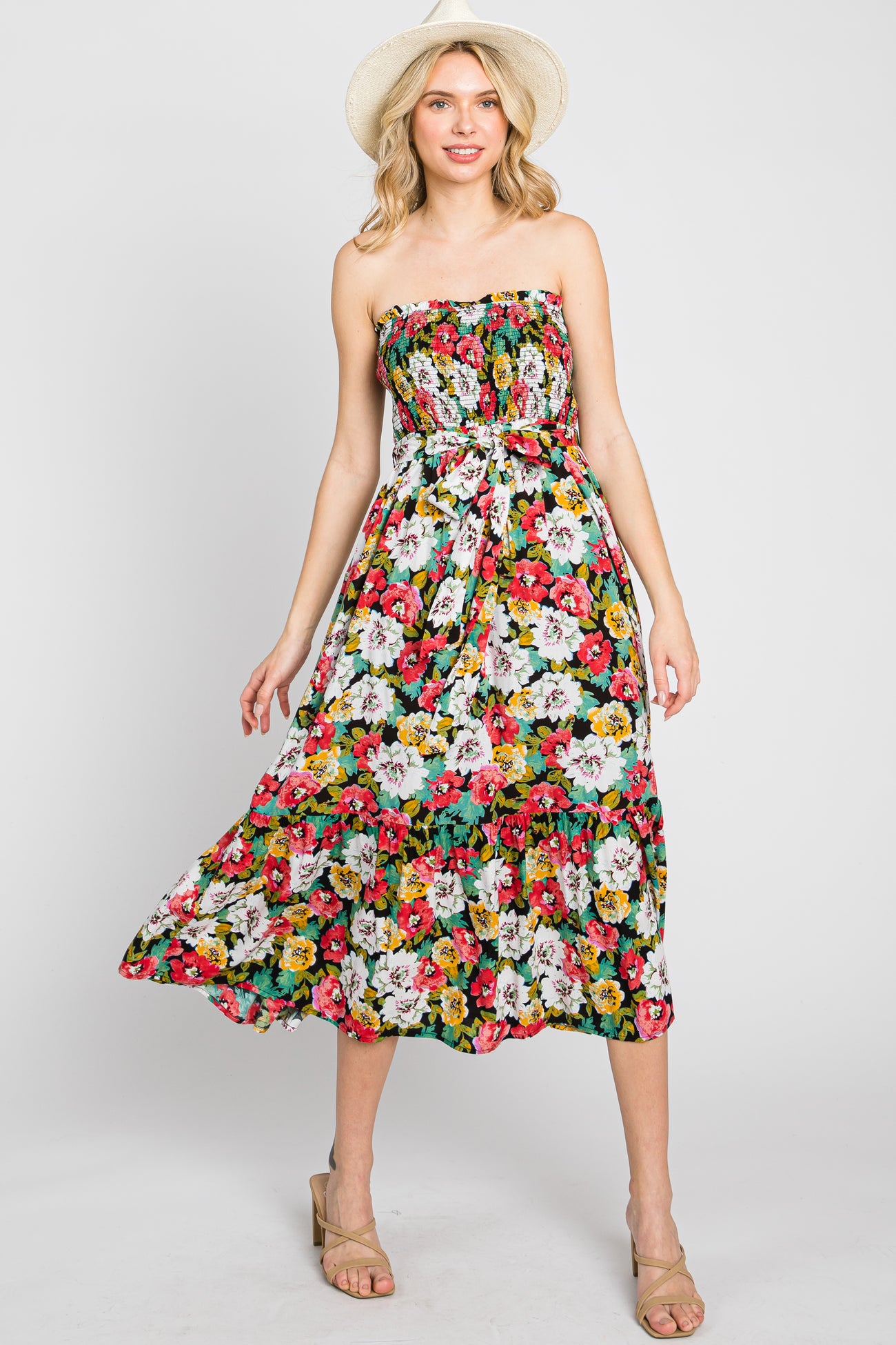 woman wearing a strapless floral midi dress and straw hat against a white background