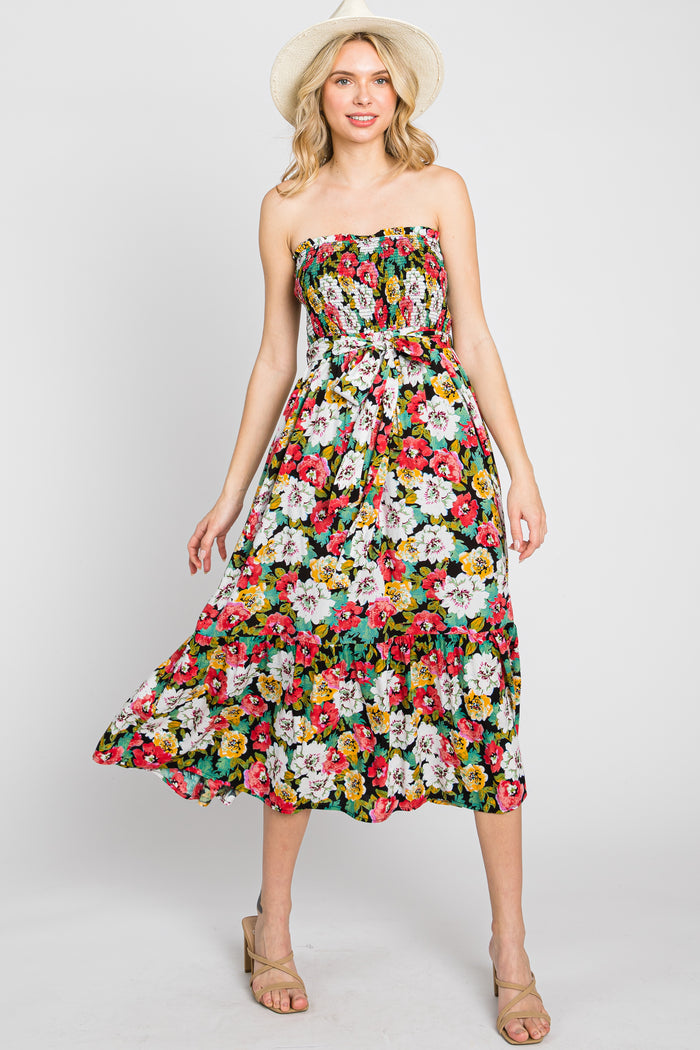 woman wearing a strapless floral midi dress and straw hat against a white background