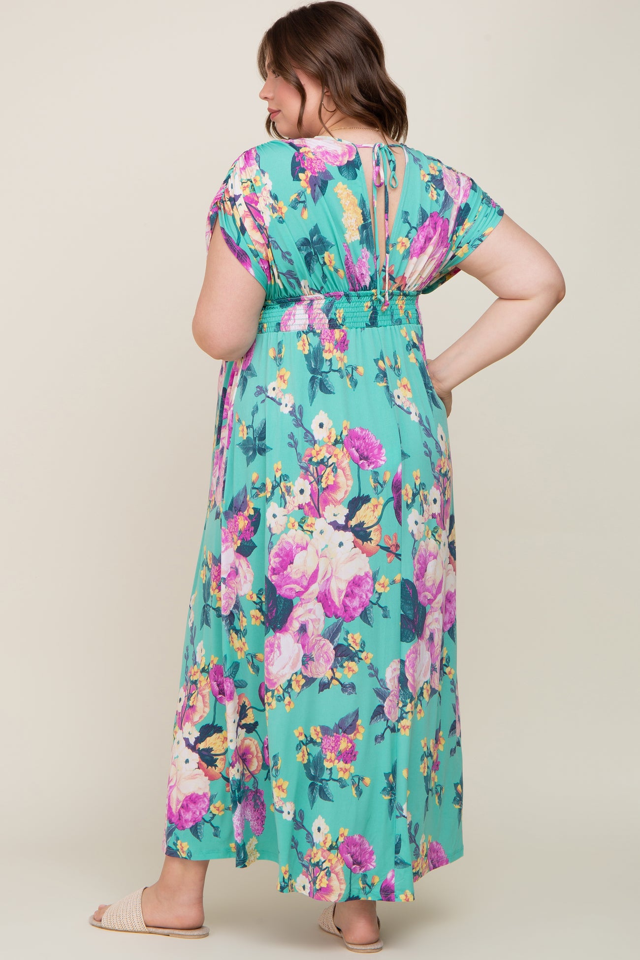 Woman wearing a mint green floral maxi dress with pink and purple flowers and a smocked waist