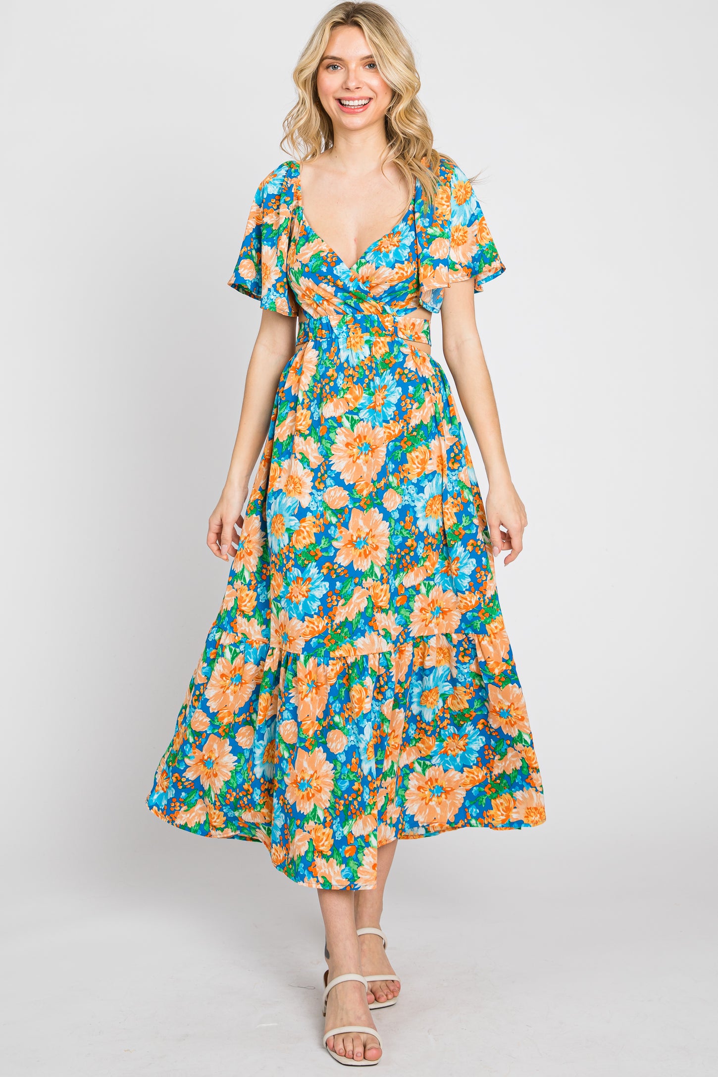 woman wearing a vibrant floral maxi dress with short flutter sleeves and a cinched waist