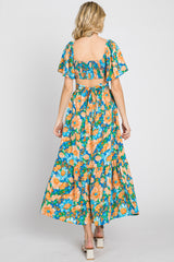 woman wearing a floral maxi dress with short sleeves and an open back, featuring vibrant orange and blue flowers