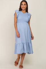 Pregnant woman wearing a light blue smocked maternity midi dress with ruffle sleeves and brown sandals