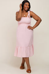 woman wearing a light pink smocked midi dress with tie straps and ruffle hem