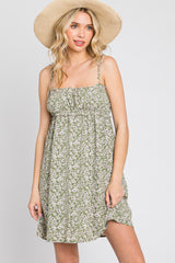 woman wearing a green floral print mini dress and a straw sun hat against a white background