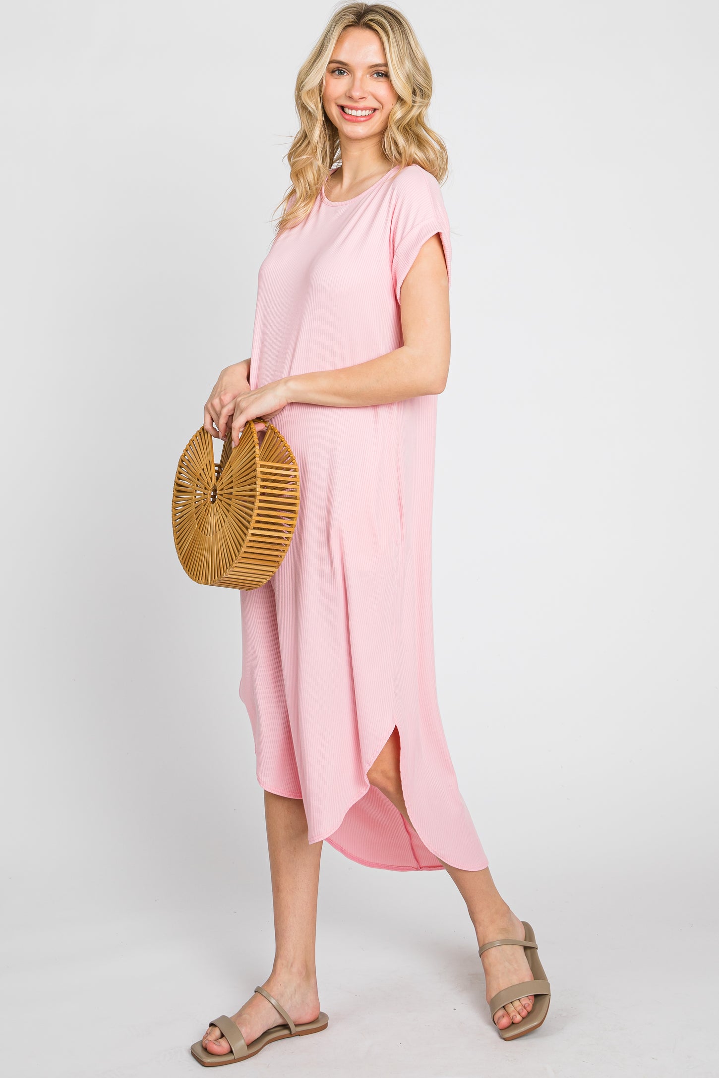 woman wearing a pink short sleeve ribbed midi dress and holding a round bamboo handbag