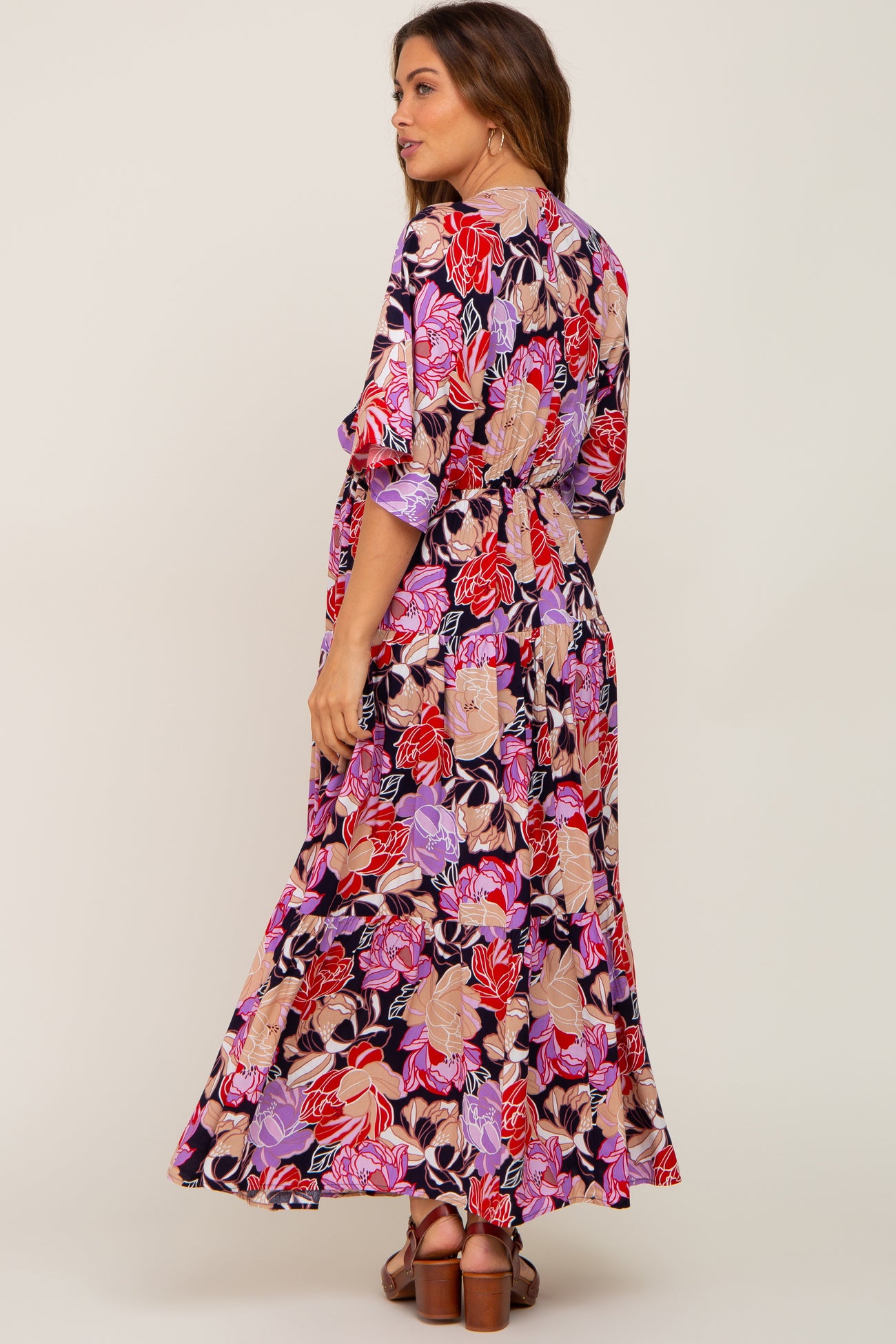 woman wearing a tiered floral maxi dress with red and purple flowers and brown platform sandals