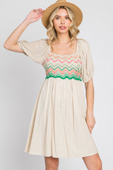 woman wearing a beige puff sleeve dress with colorful crochet bodice and a straw hat