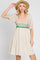 woman wearing a beige puff sleeve dress with colorful crochet bodice and a straw hat