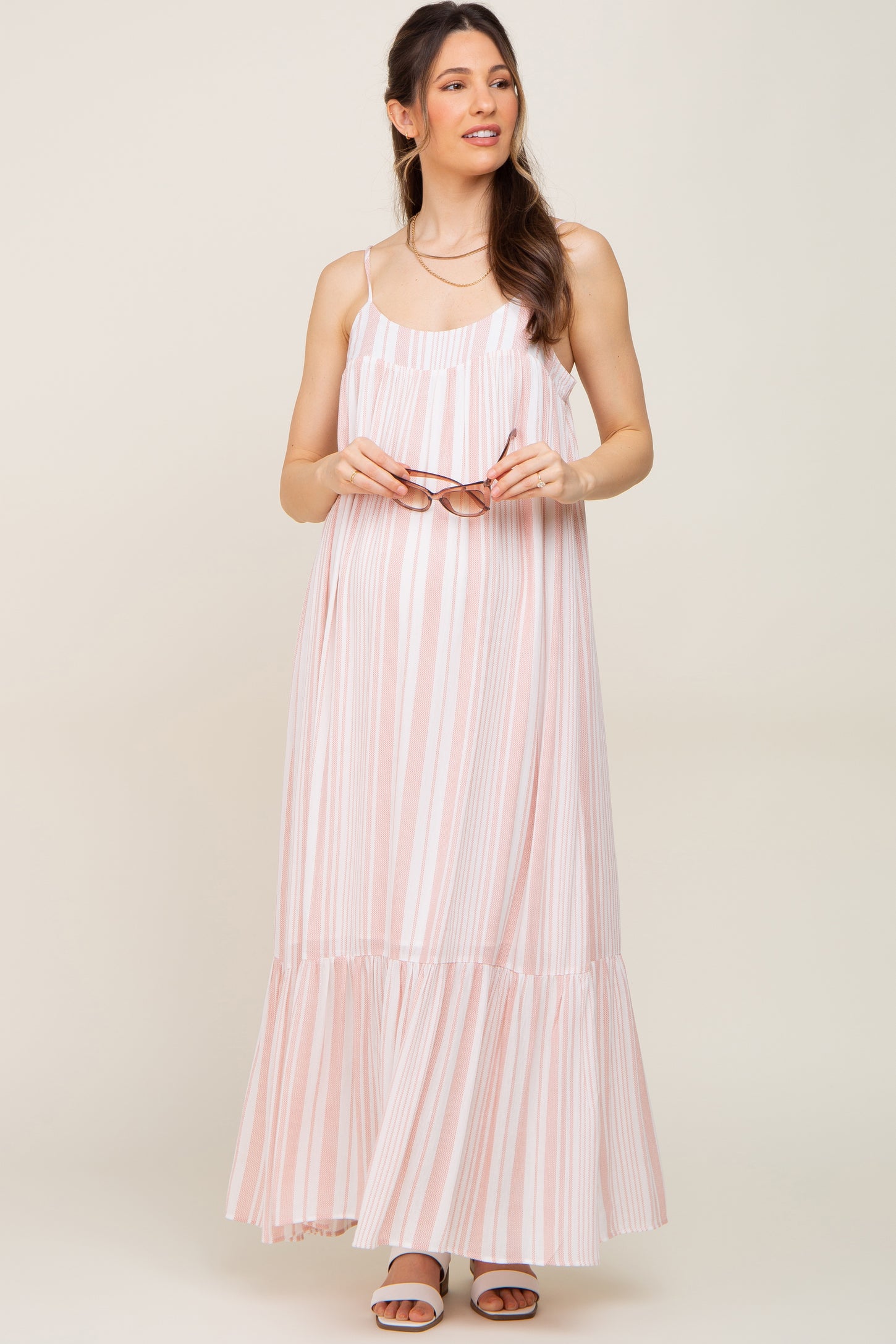 pregnant woman in pink and white striped maternity maxi dress holding sunglasses