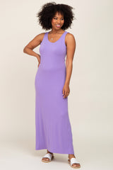 Woman with afro hair wearing a purple sleeveless maxi dress and white slide sandals