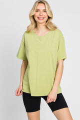 woman wearing an oversized lime green t-shirt and black biker shorts against a white background