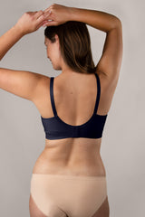 Rear view of a woman wearing a navy blue wireless bra with wide straps and beige seamless panties