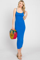 woman wearing a blue ribbed maxi dress with spaghetti straps and holding a colorful woven handbag