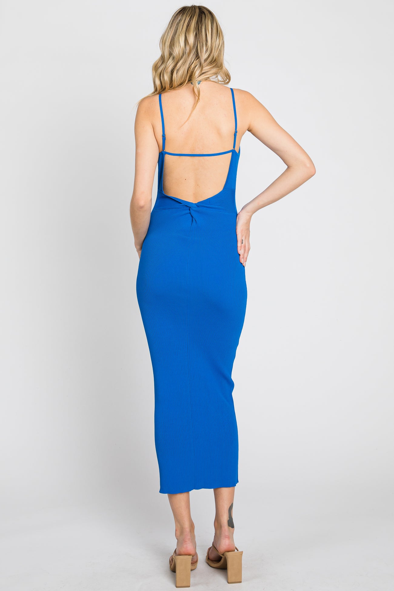 woman wearing a blue ribbed midi dress with a back cutout and spaghetti straps