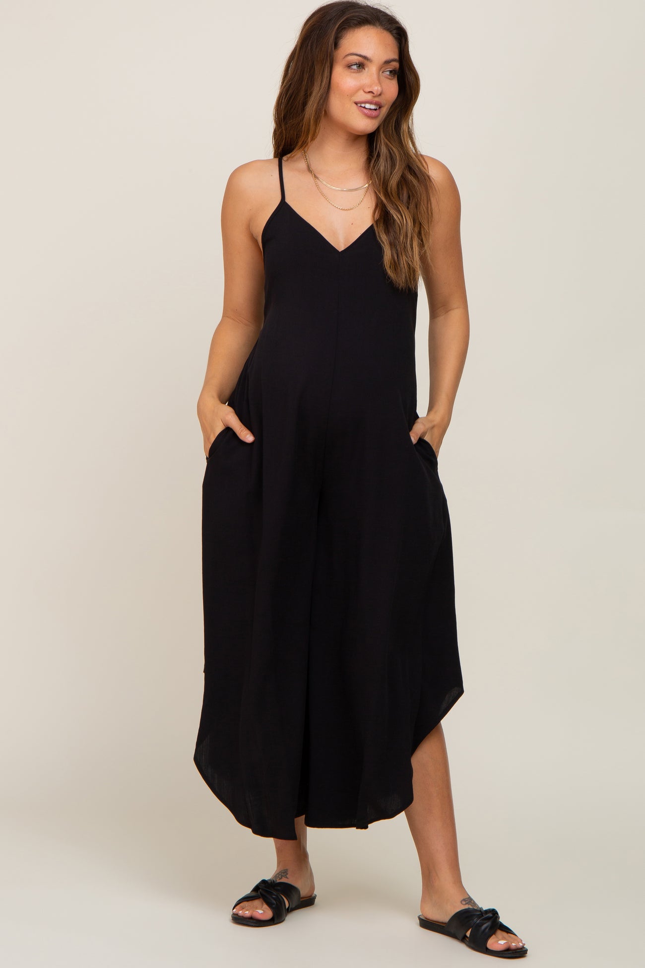 woman wearing a black sleeveless maternity jumpsuit with pockets and wide legs