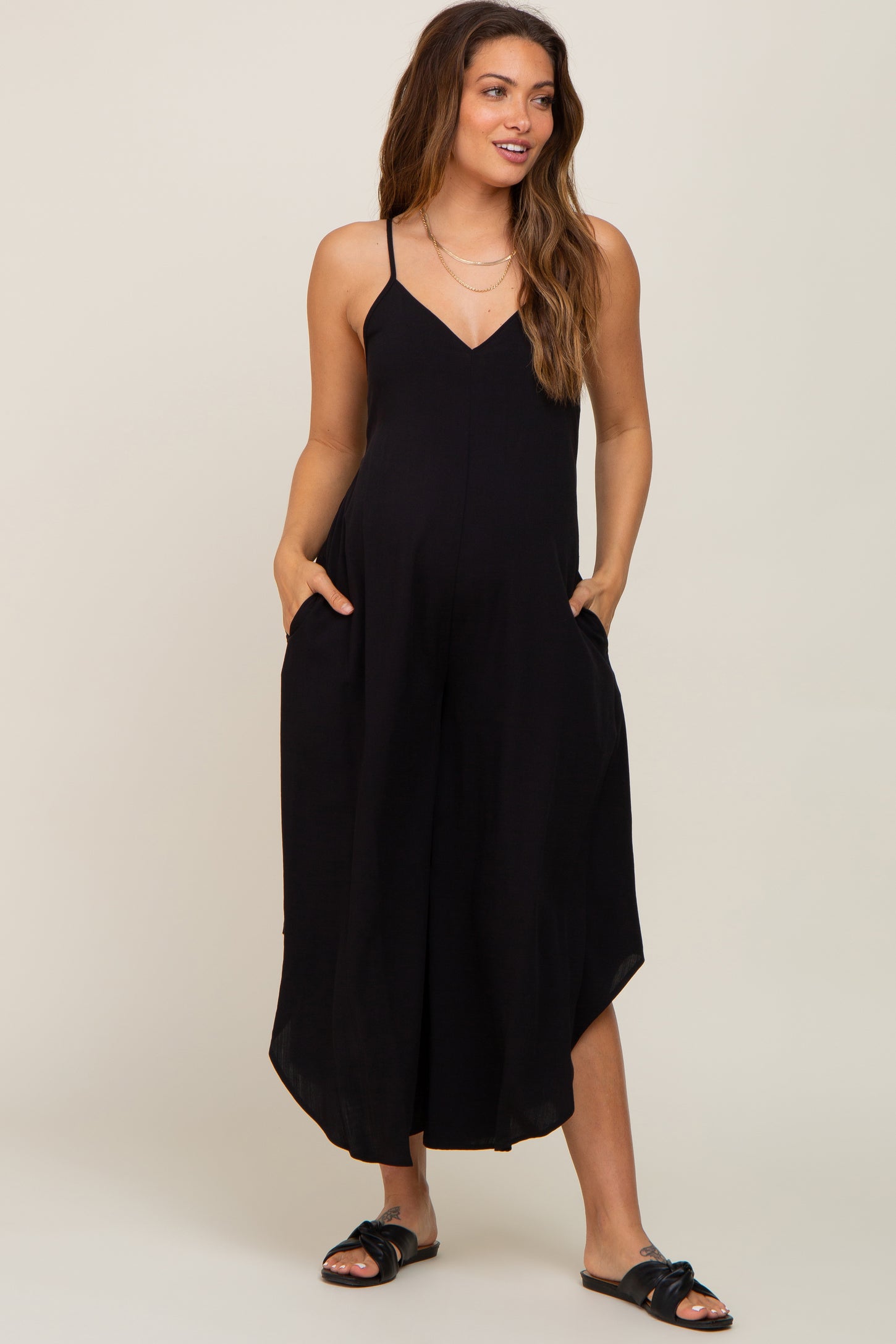 woman wearing a black sleeveless maternity jumpsuit with pockets and wide legs
