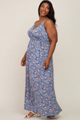 smiling woman wearing a blue floral sleeveless maxi dress with a waist tie and white sandals