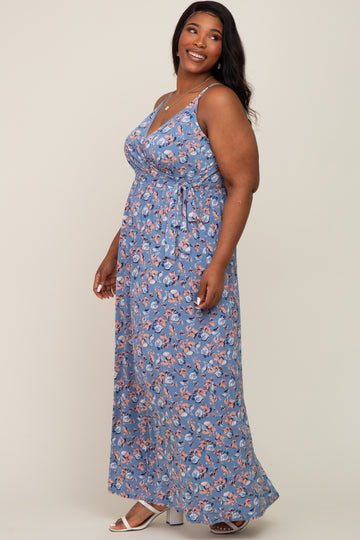 smiling woman wearing a blue floral sleeveless maxi dress with a waist tie and white sandals