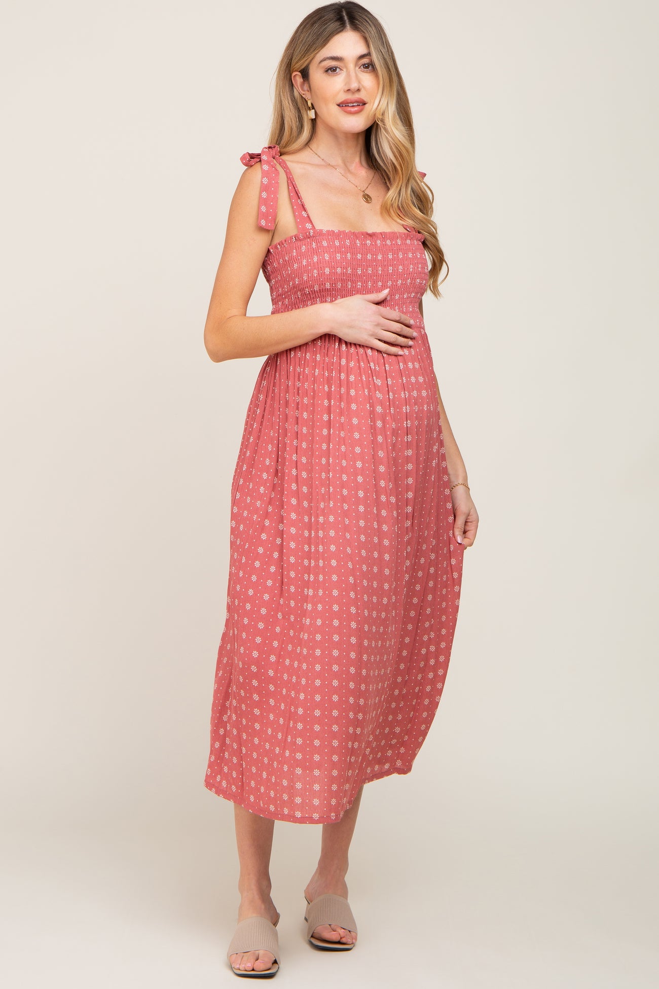 pregnant woman in a pink floral smocked maternity midi dress with tie straps and a square neckline