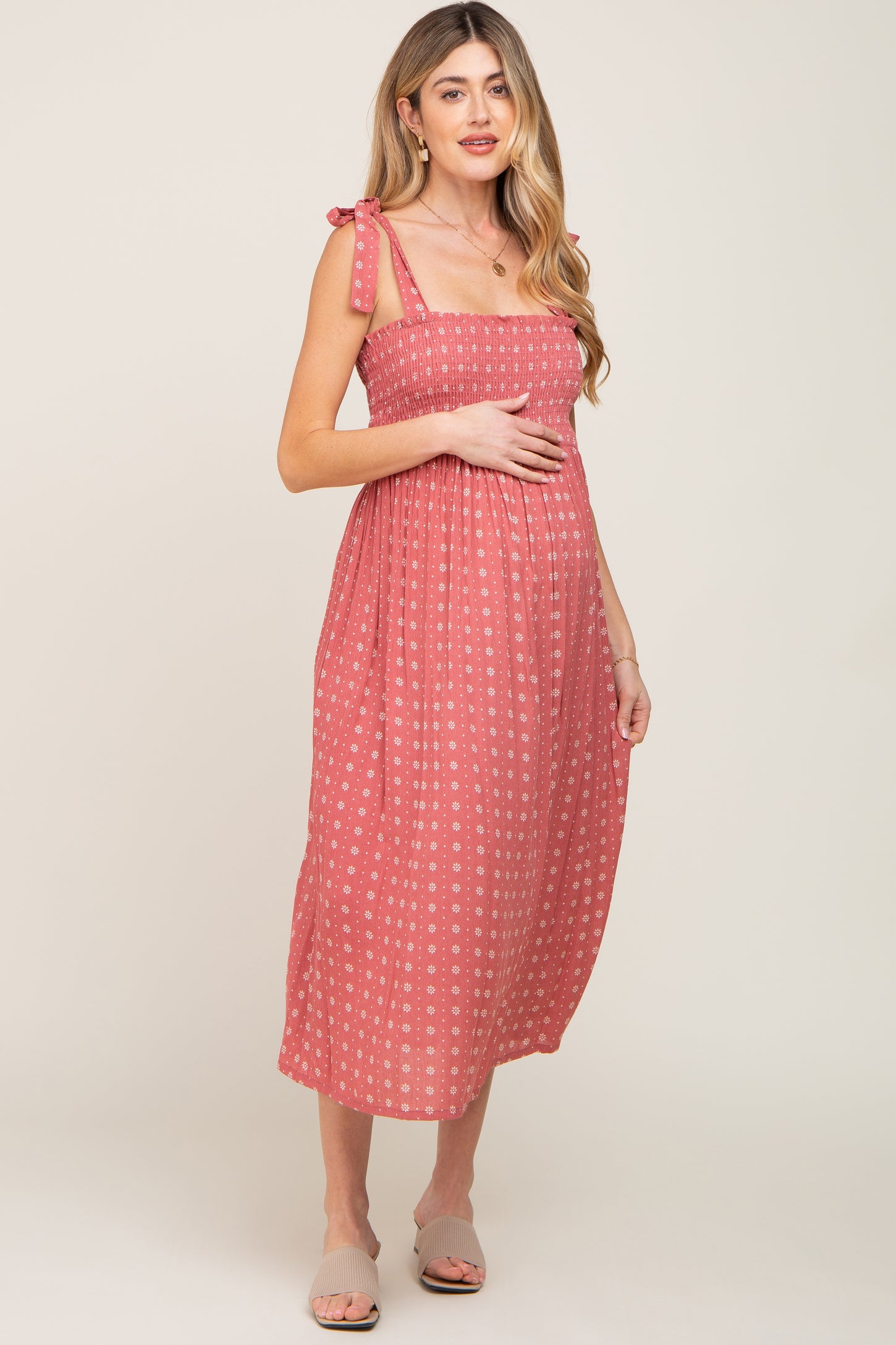 pregnant woman in a pink floral smocked maternity midi dress with tie straps and a square neckline
