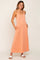 woman wearing a peach sleeveless maxi dress with pockets and white slide sandals