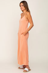 woman wearing a peach sleeveless maxi dress with pockets and white slide sandals