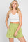 woman wearing white ribbed crop tank top and lime green paperbag waist shorts