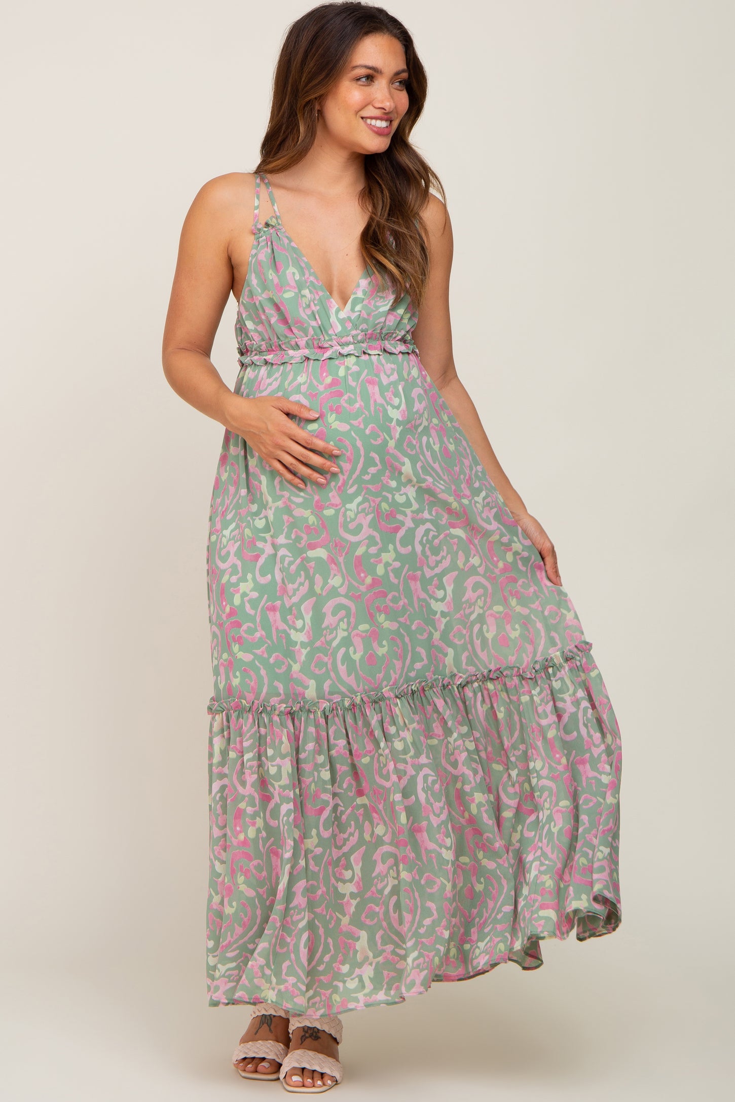 smiling pregnant woman wearing a green and pink floral print maternity maxi dress with ruffle details