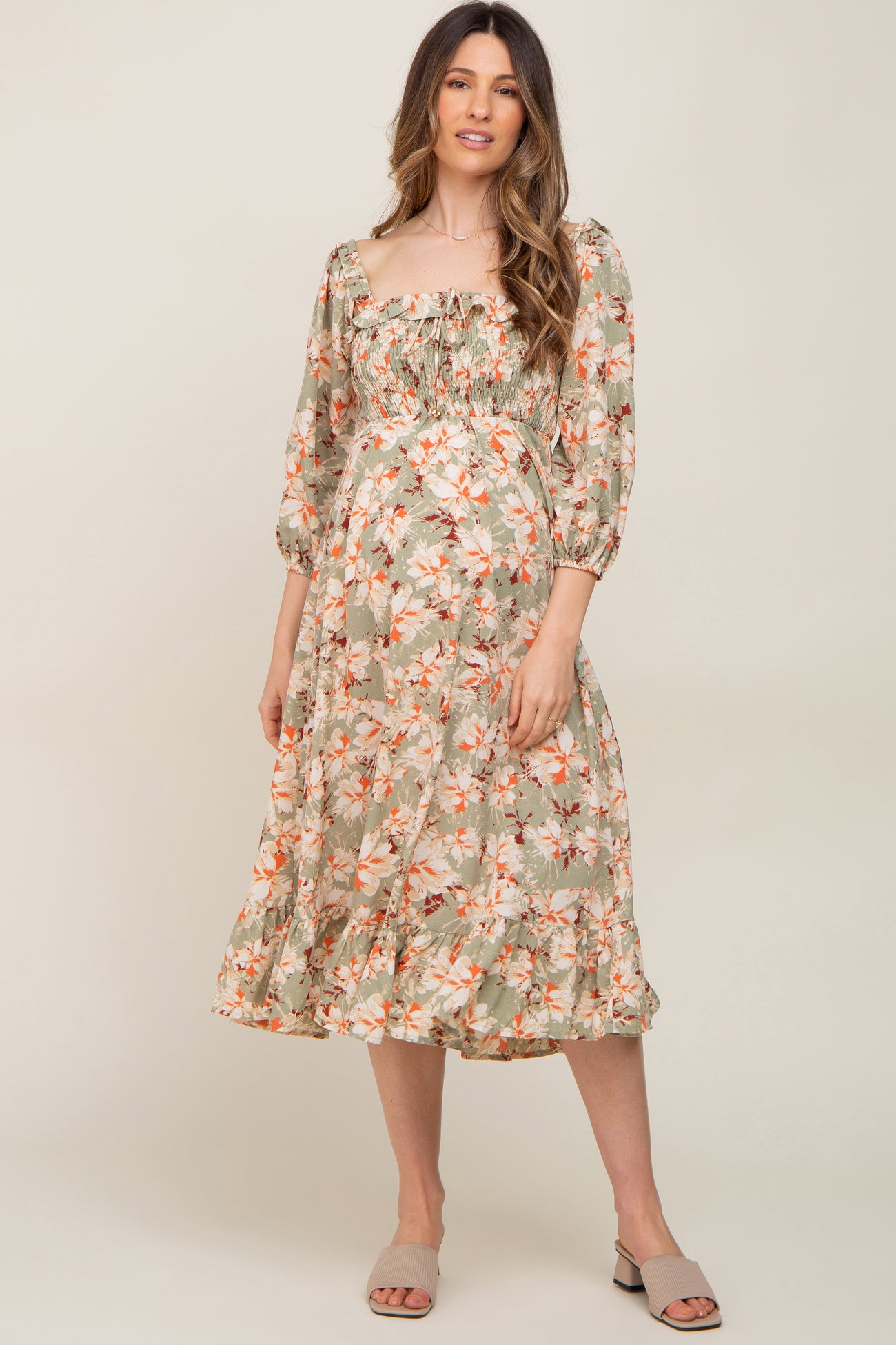 woman wearing a floral print maternity dress with a square neckline and puffed sleeves, showcasing her baby bump