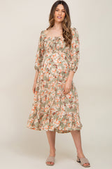 woman wearing a floral print maternity dress with a square neckline and puffed sleeves, showcasing her baby bump