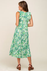 Woman wearing a green and white paisley print tiered midi dress with ruffle sleeves and brown clogs