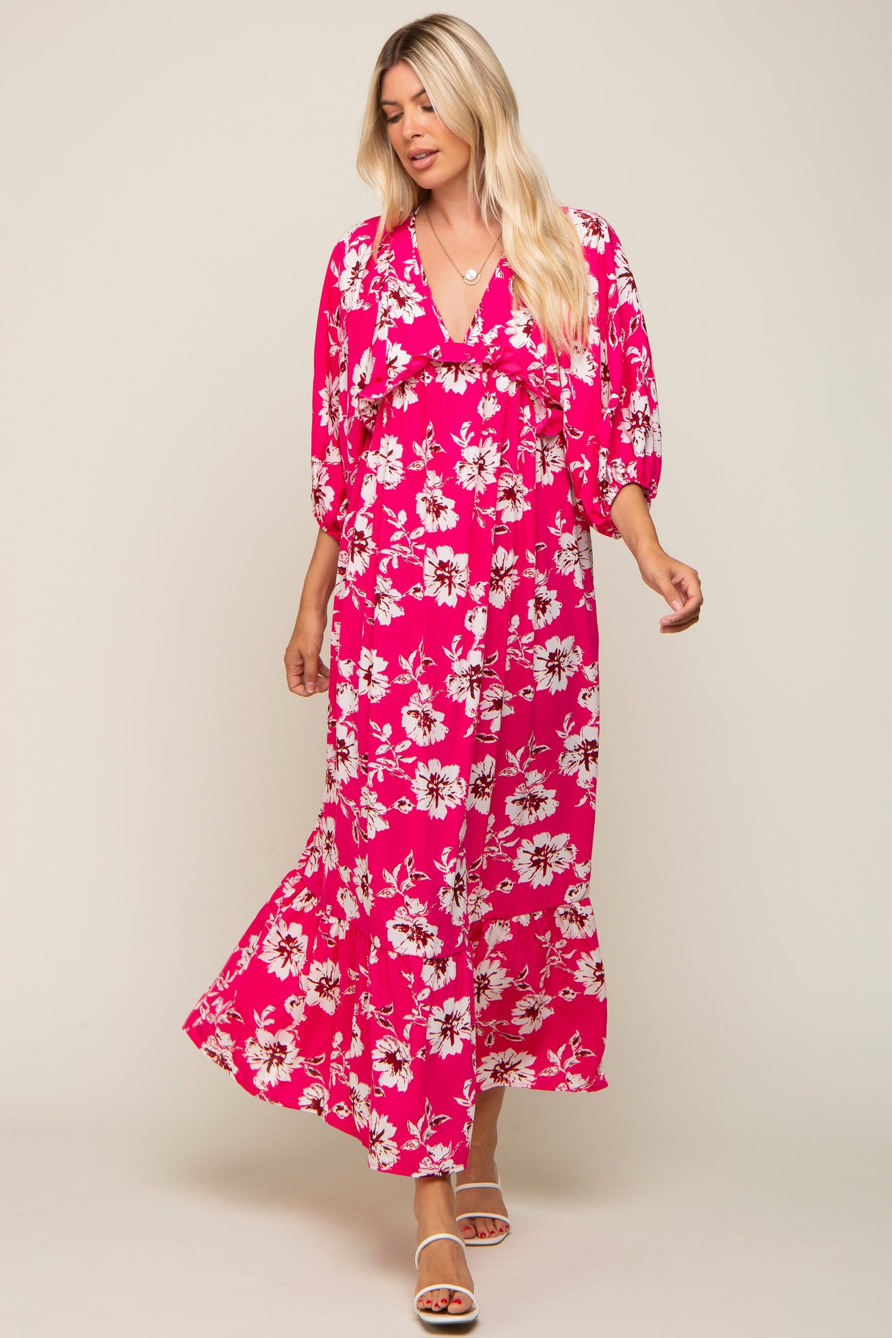 woman wearing a pink floral maxi dress with a v-neck and puff sleeves, standing in a relaxed pose
