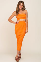 woman wearing orange ribbed tube top and matching midi skirt set with brown platform sandals